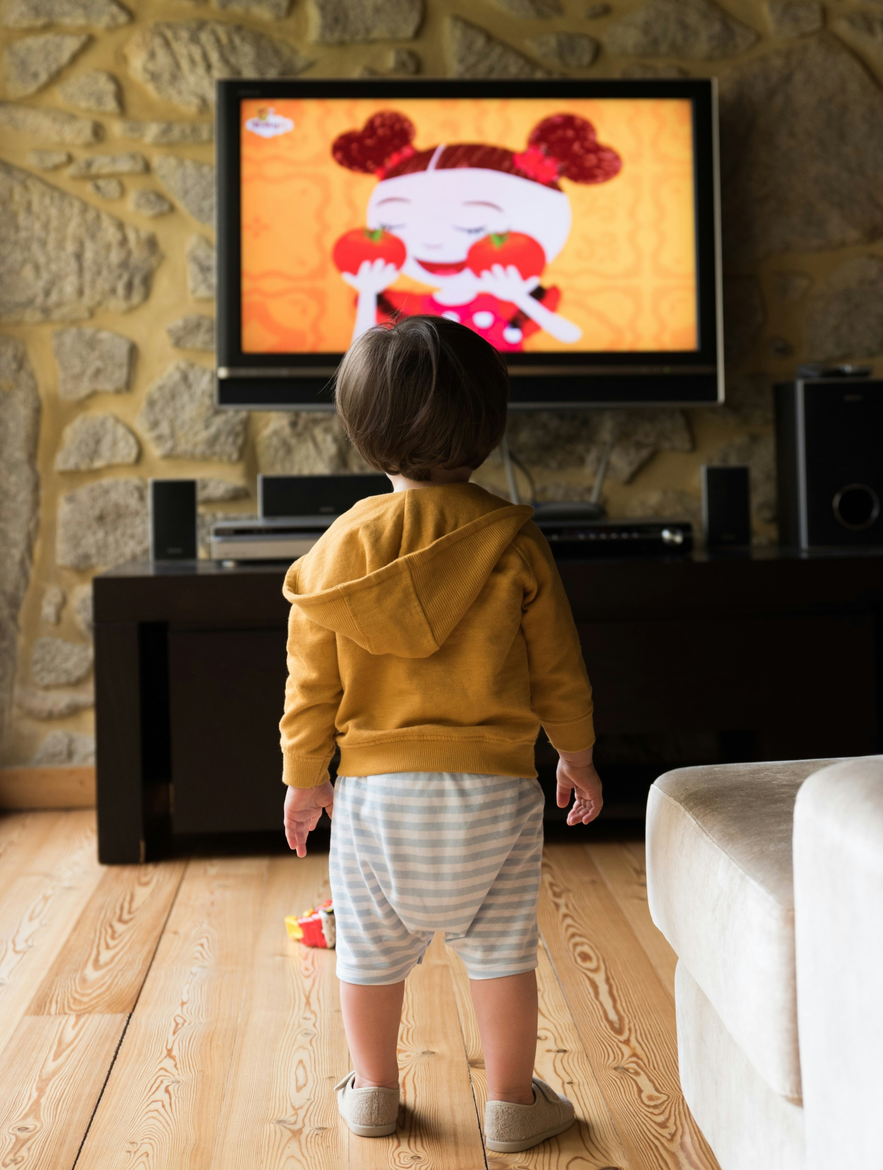 A small child standing in front of a television