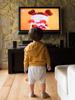 A small child standing in front of a television