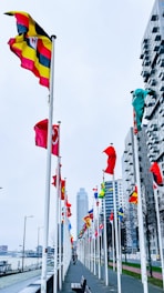 A walkway lined with lots of flags next to tall buildings
