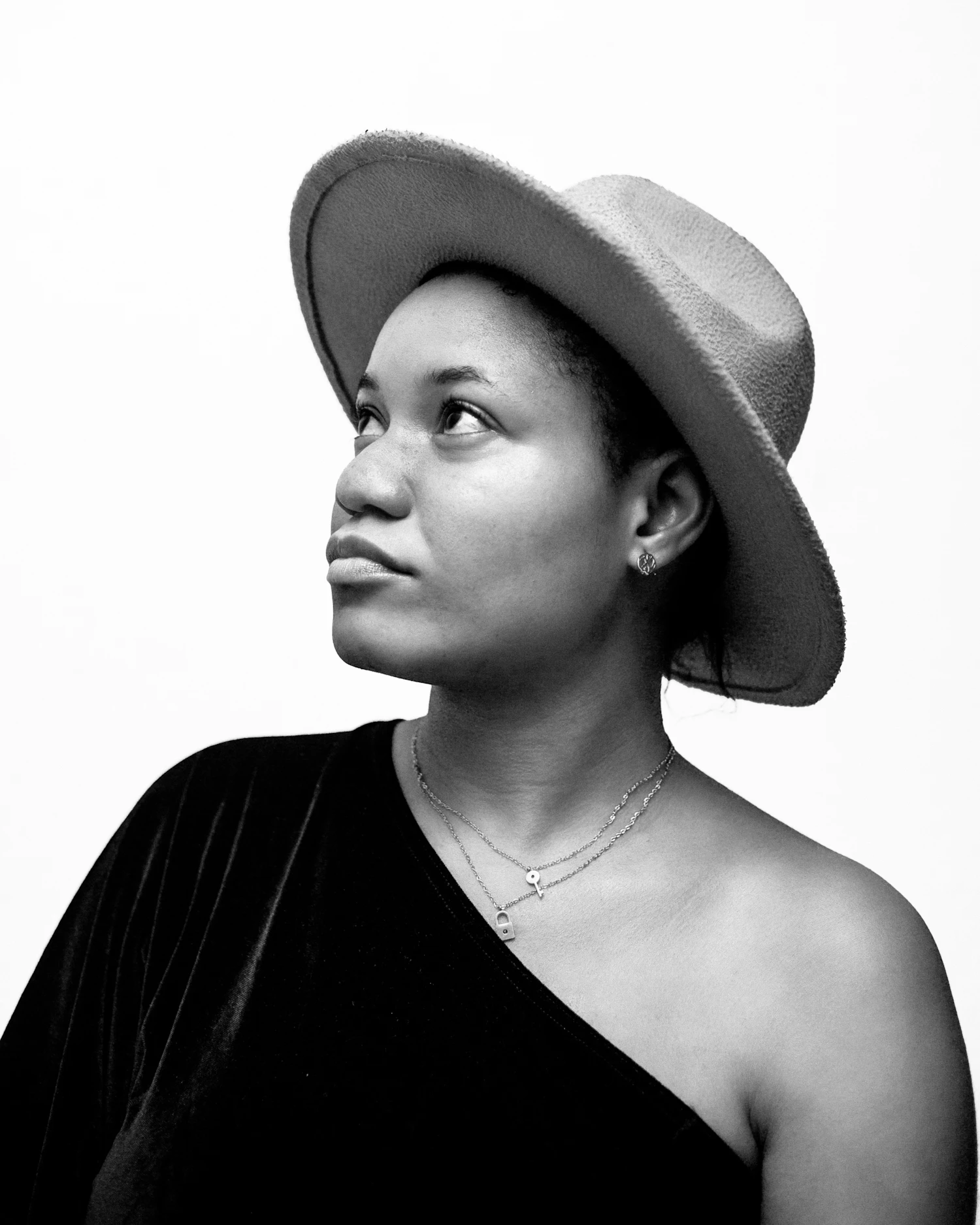 A woman in a wide felt hat, head turned away from the light