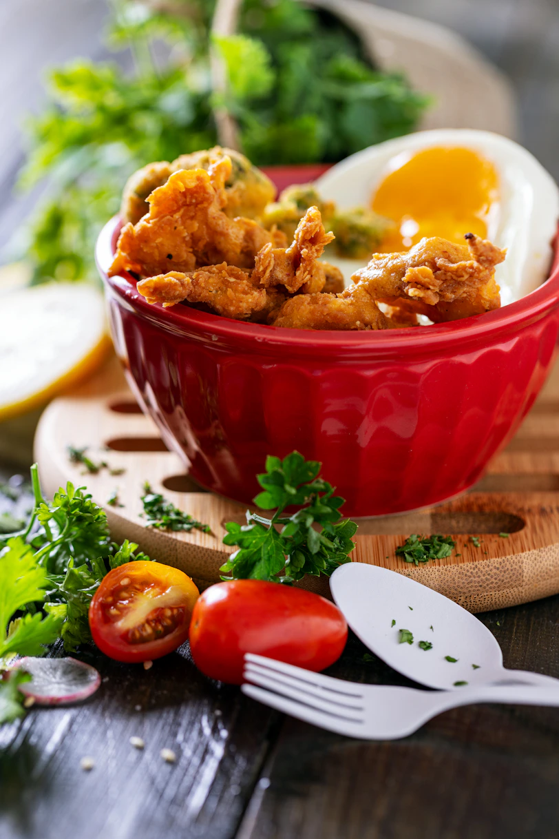 A red bowl filled with fried eggs on top of a wooden cutting board