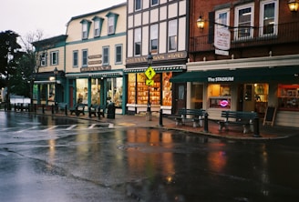 A wet city street with a row of buildings