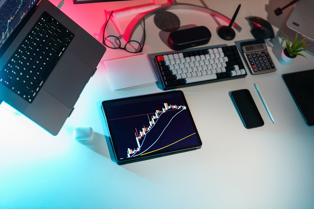 A laptop computer sitting on top of a white desk, finance office space crypto currency chart laptop tablet business analytics
