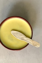 A spoon in a bowl with a liquid inside of it