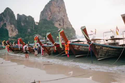 Longtail boats line a beautiful beach.