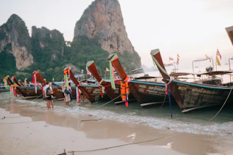 Longtail boats line a beautiful beach.