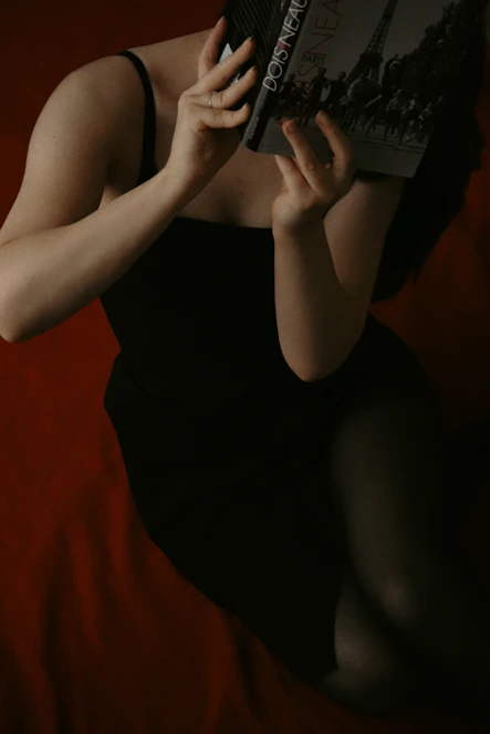 A woman in a black dress reading a book