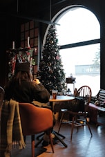 A person sitting at a table in front of a christmas tree