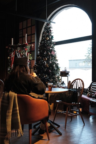 A person sitting at a table in front of a christmas tree