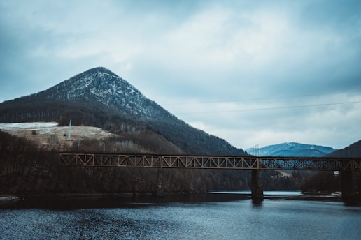 A bridge over a body of water with mountains in the background