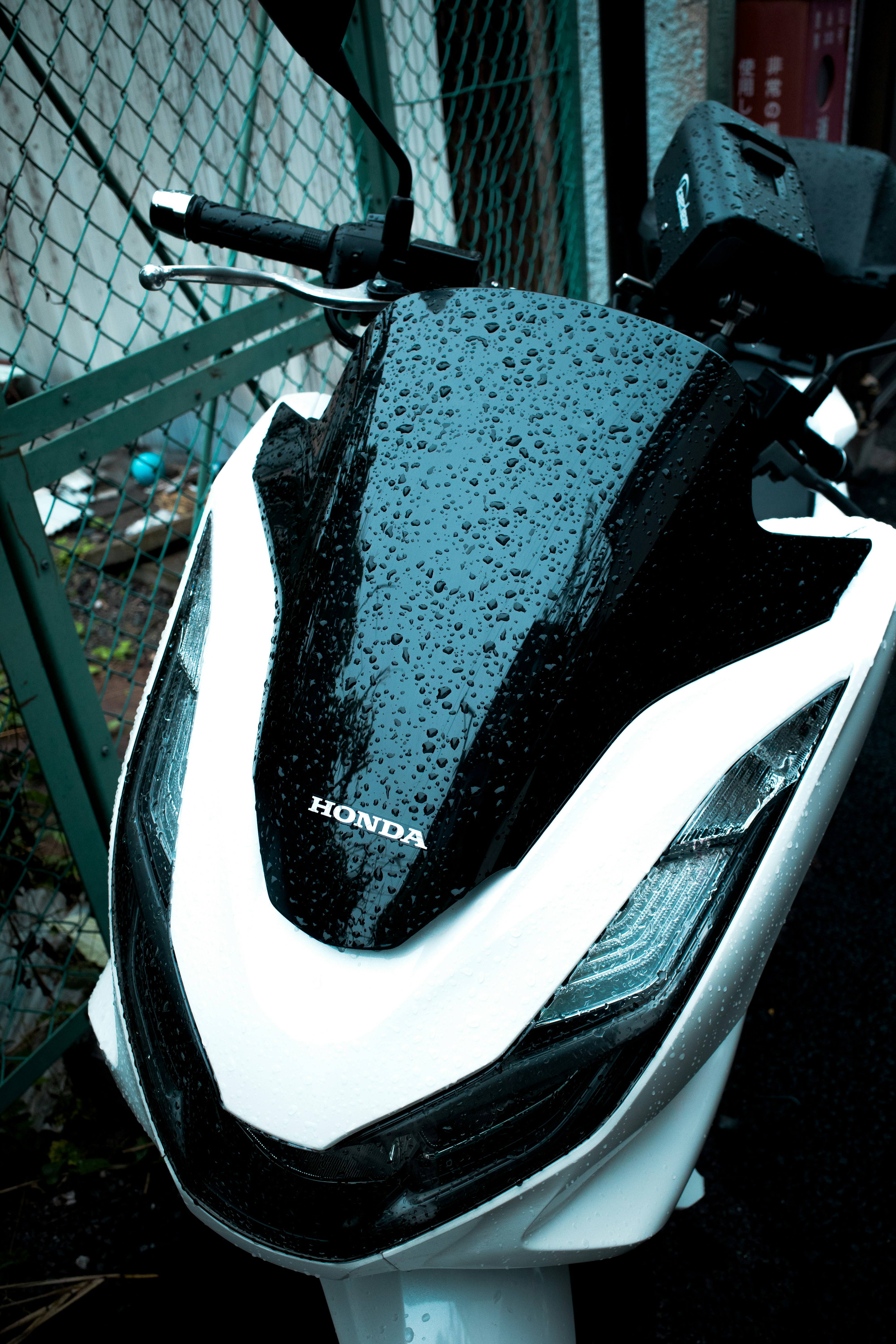 A white and black motorcycle parked next to a fence