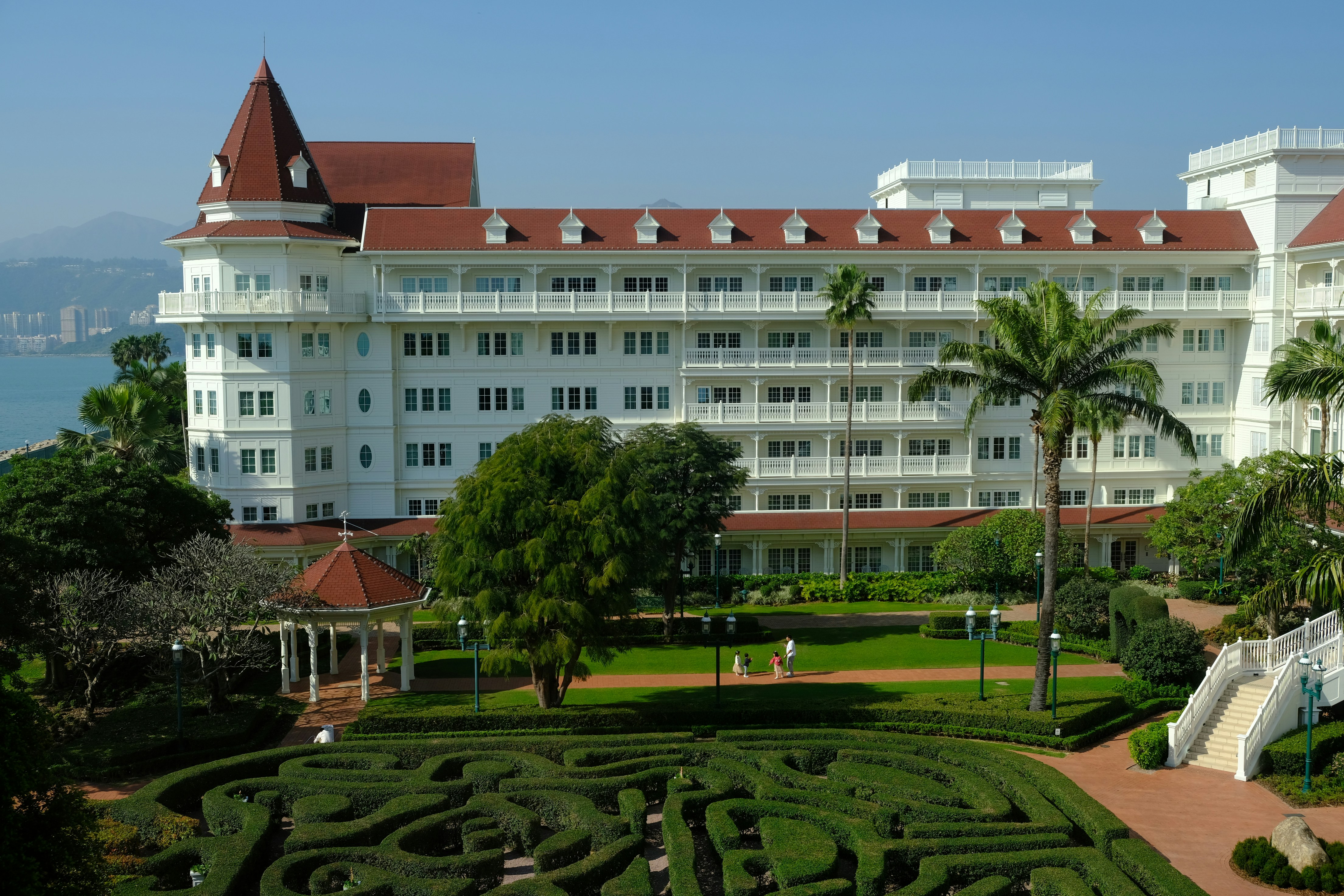 A large white building sitting next to a lush green park