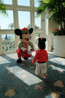 A little boy standing next to a mickey mouse