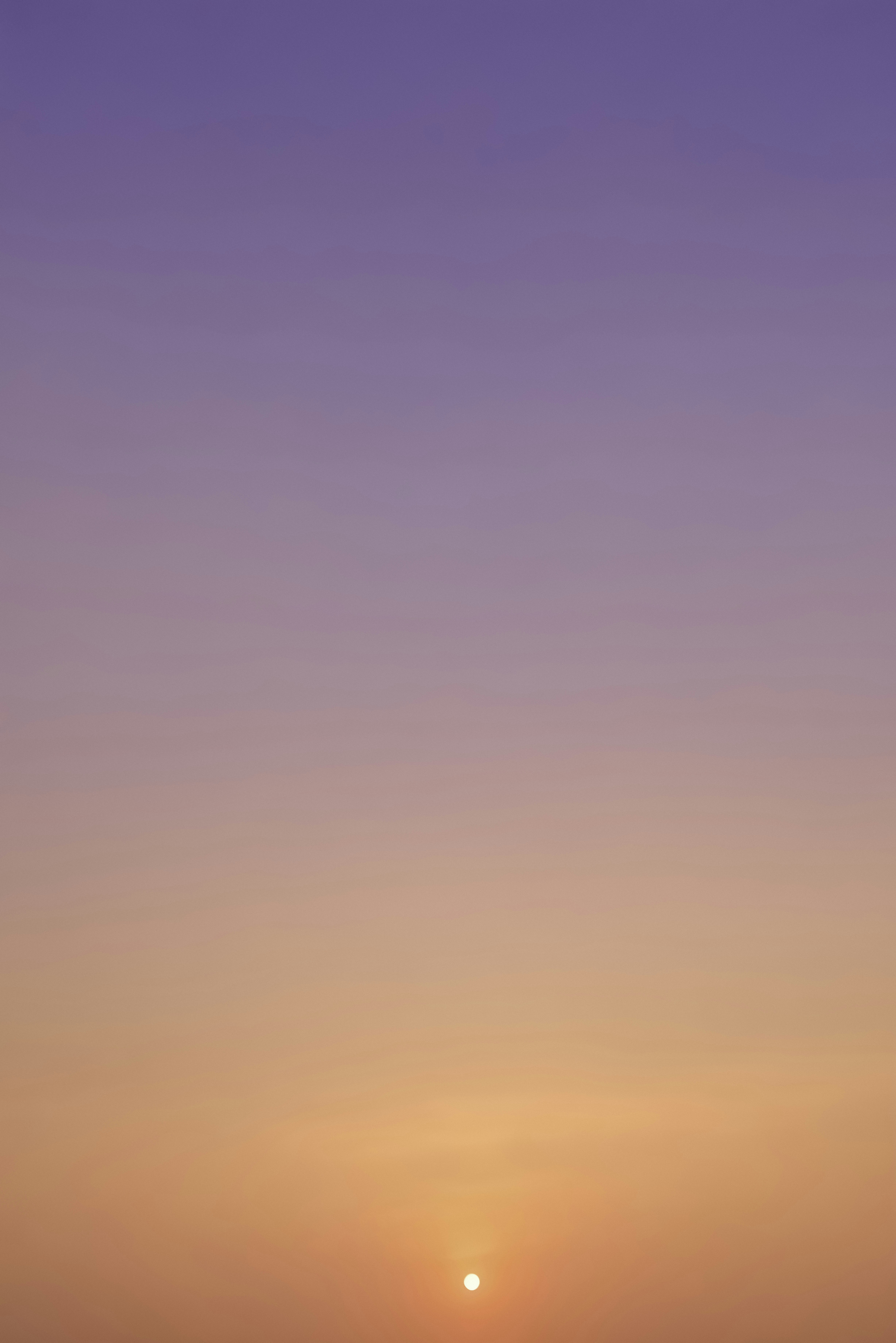 The sun is setting on the horizon of a beach