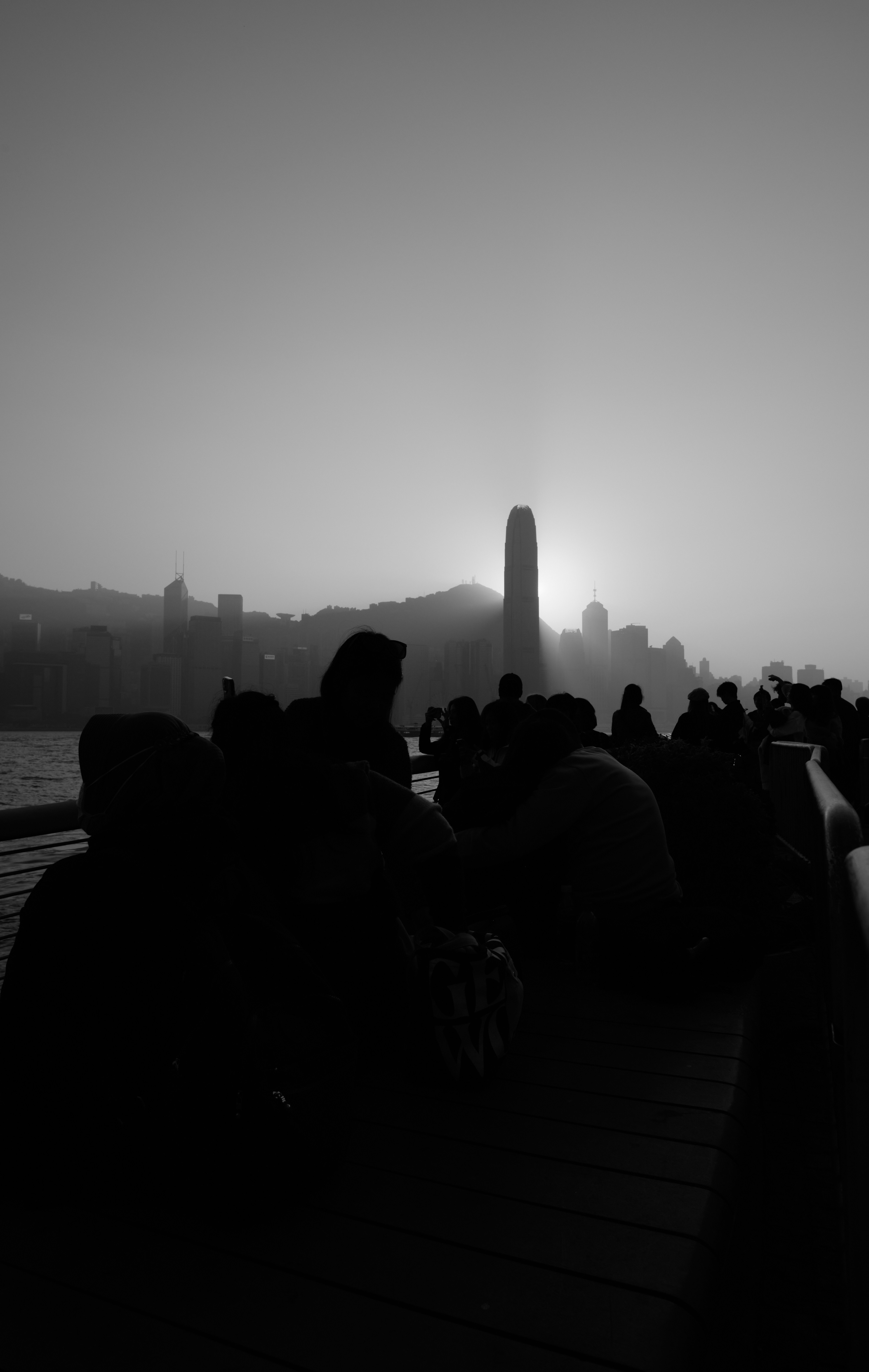 A black and white photo of people sitting on a pier