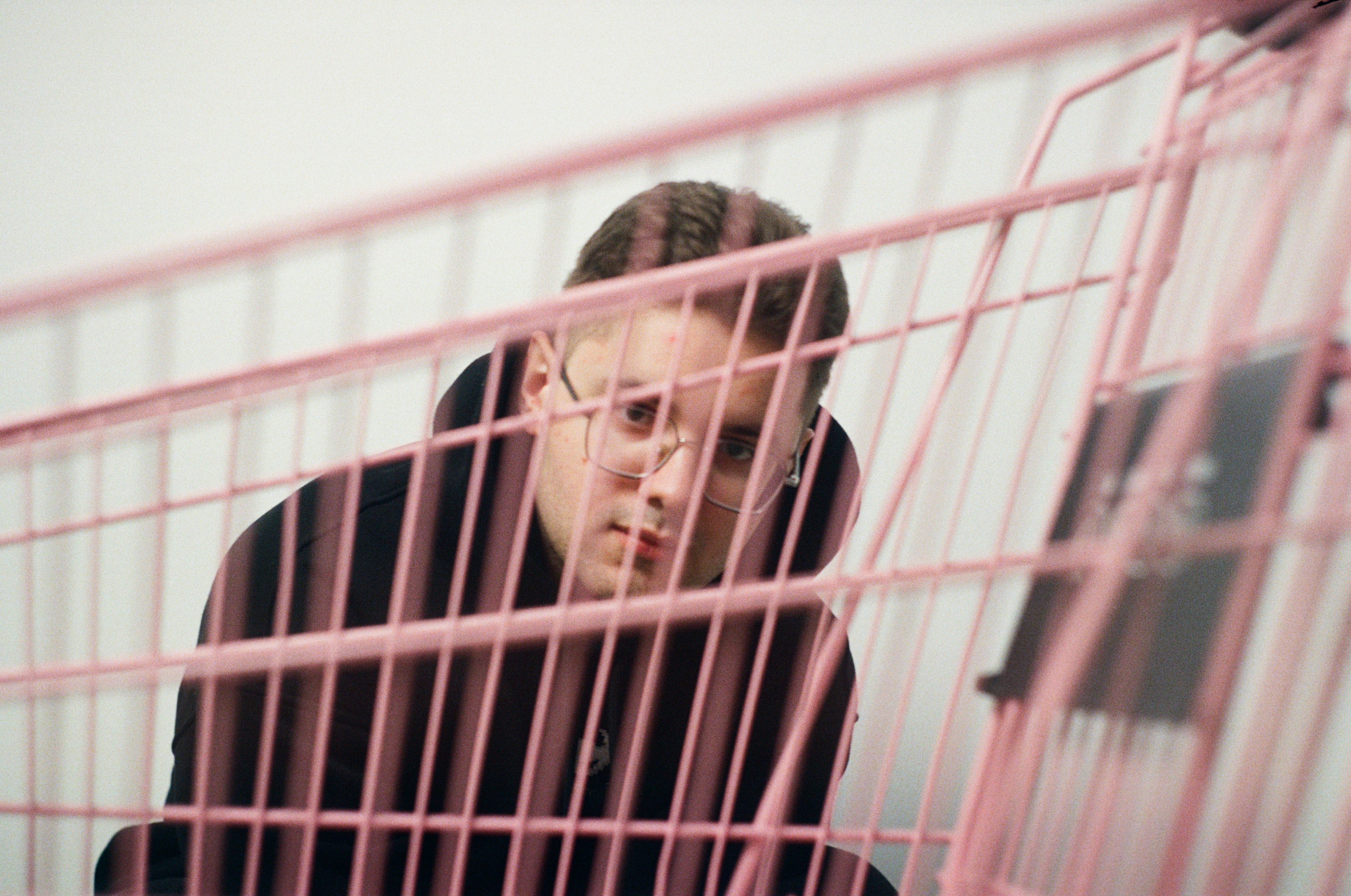 A man in a pink cage looking at a cell phone