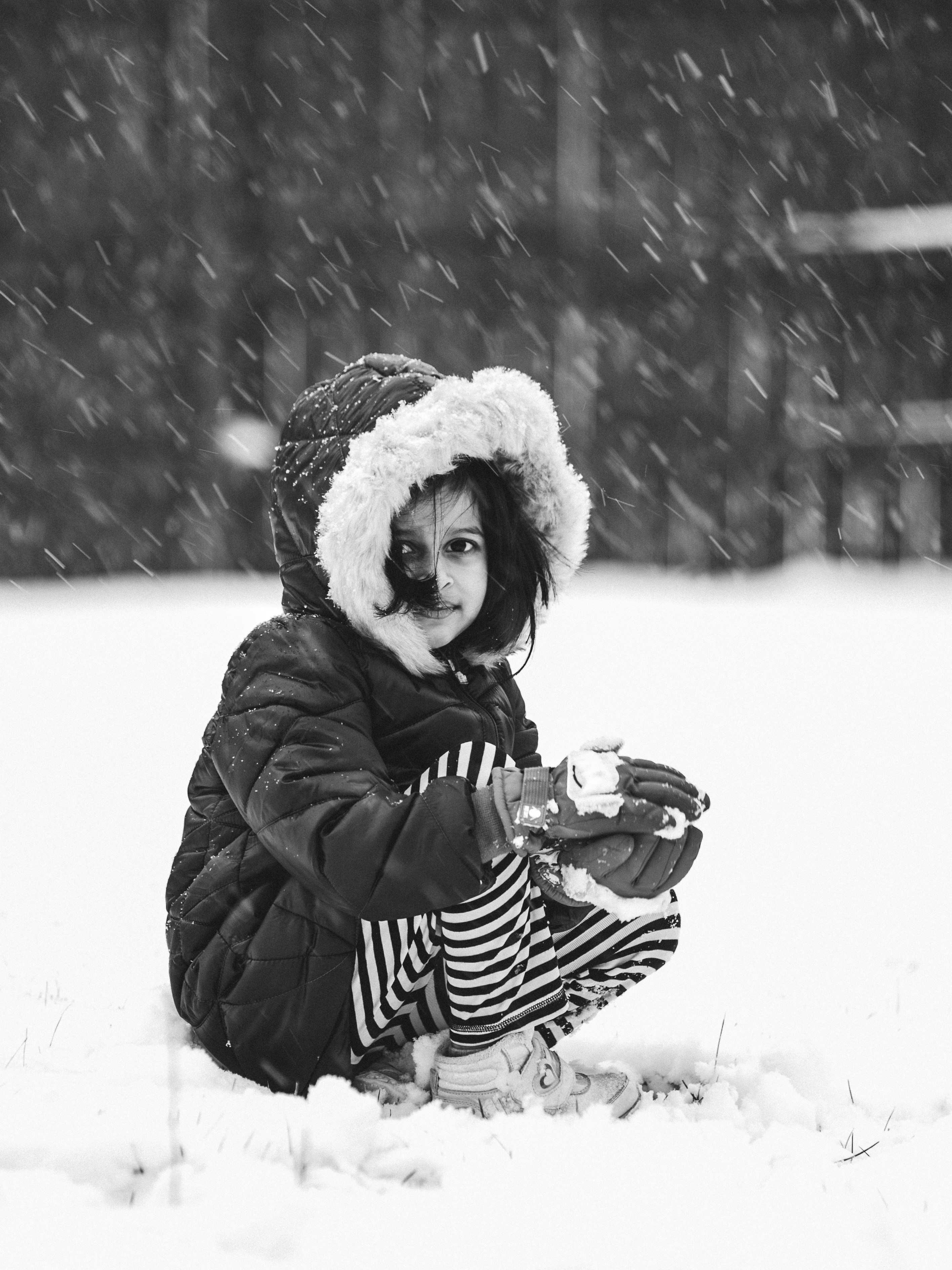 A little girl sitting in the snow with a hat on