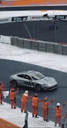 A group of people standing around a car on a race track