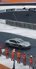 A group of people standing around a car on a race track