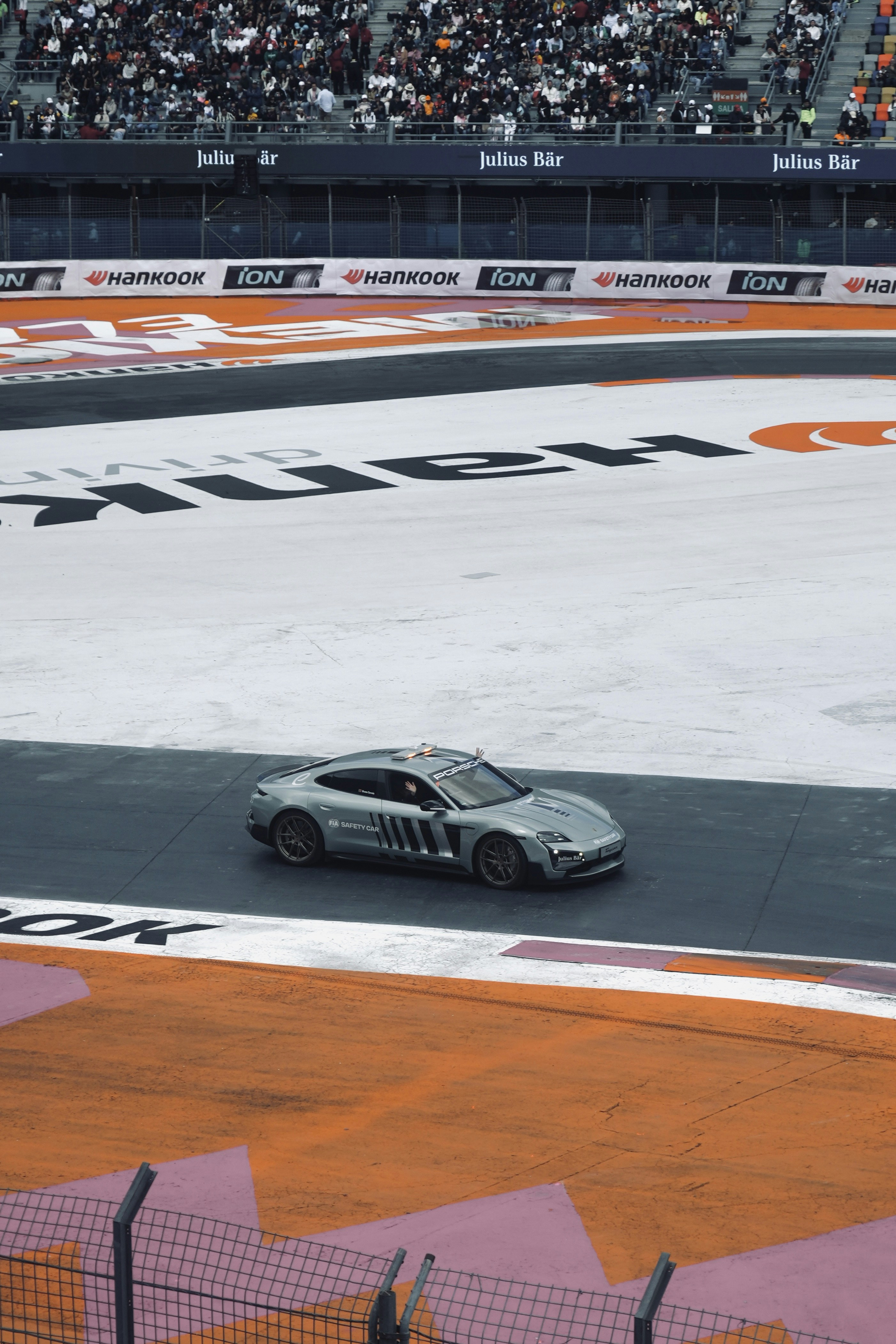 Un'auto che percorre una pista da corsa davanti a una folla