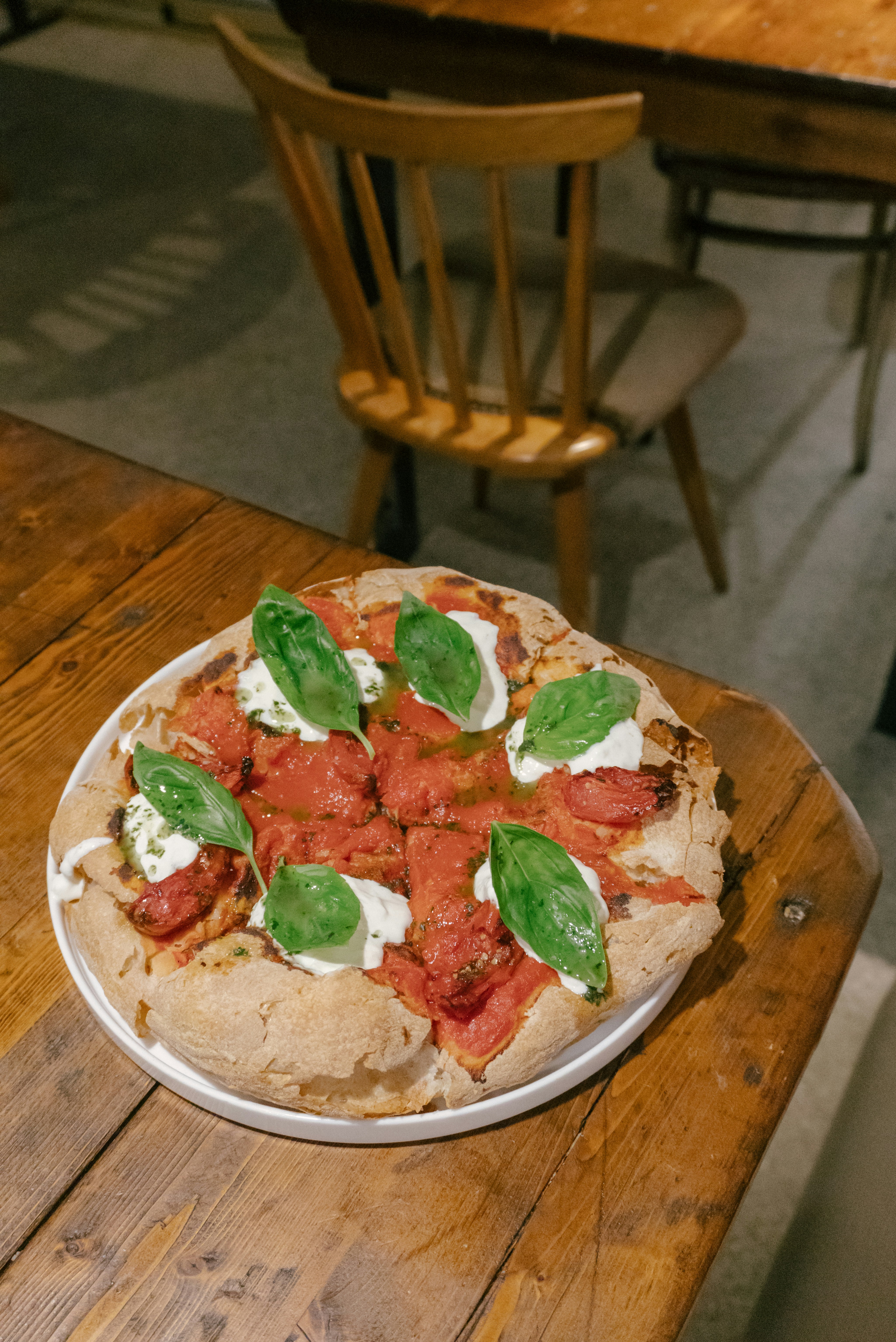 Pizza fraîchement cuite avec sauce tomate et basilic sur une table en bois.