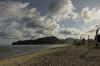A sandy beach next to the ocean under a cloudy sky