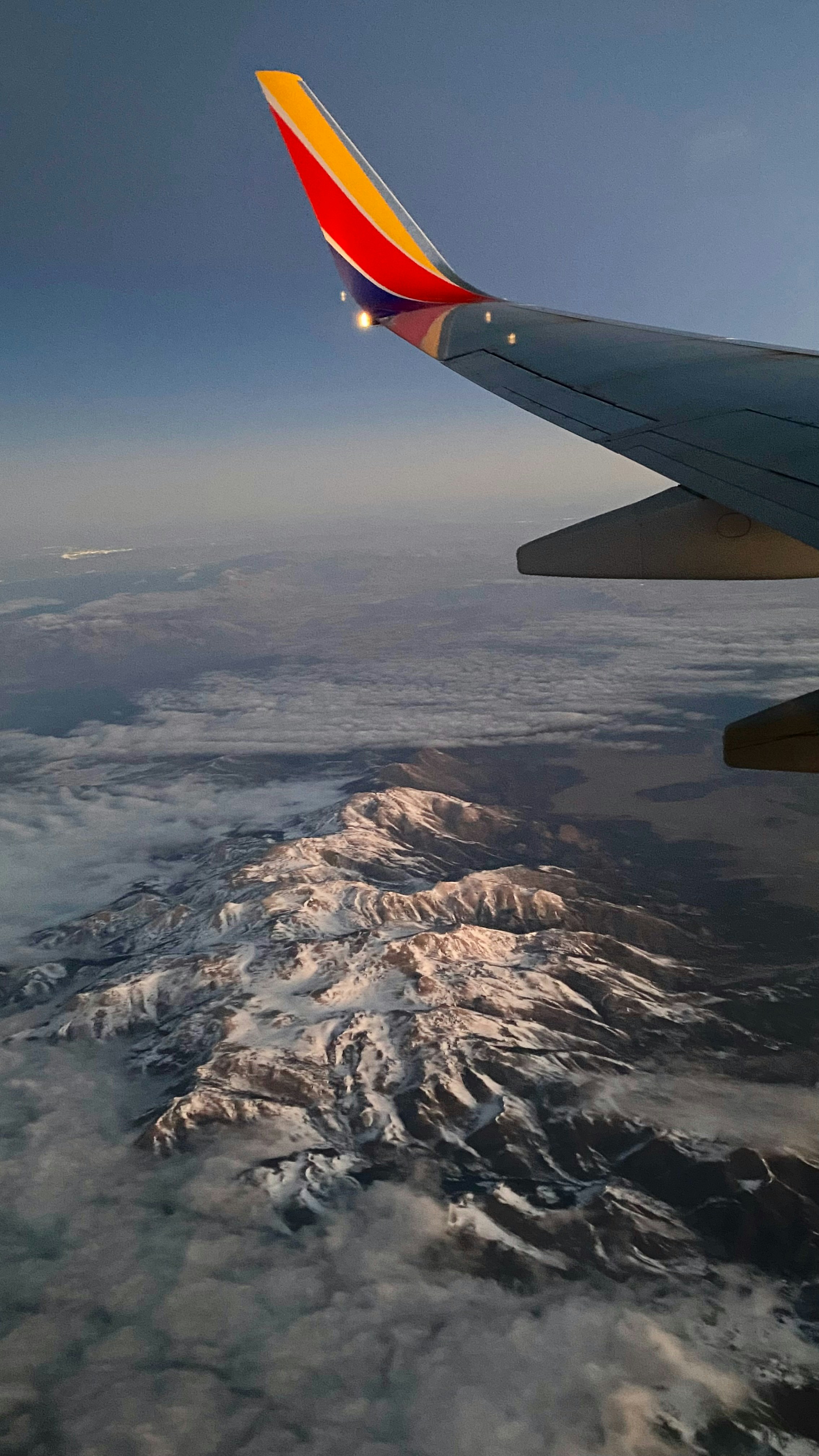 The wing of a plane flying over a mountain range