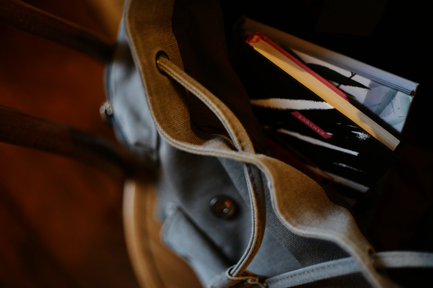 A soft leather bag held open to show the notebook and pencil packed inside it