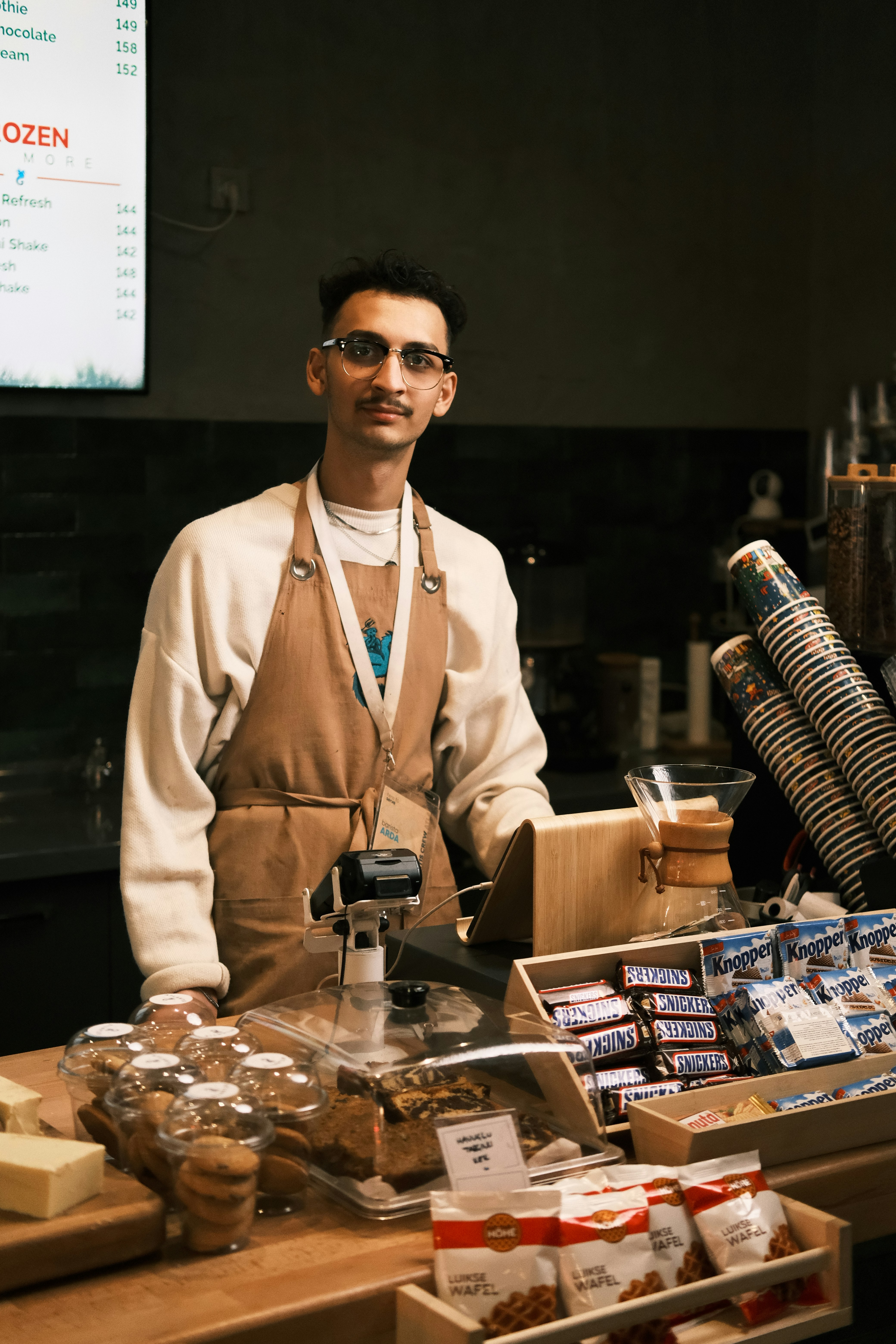 A man standing behind a counter filled with food