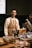 A man standing behind a counter filled with food