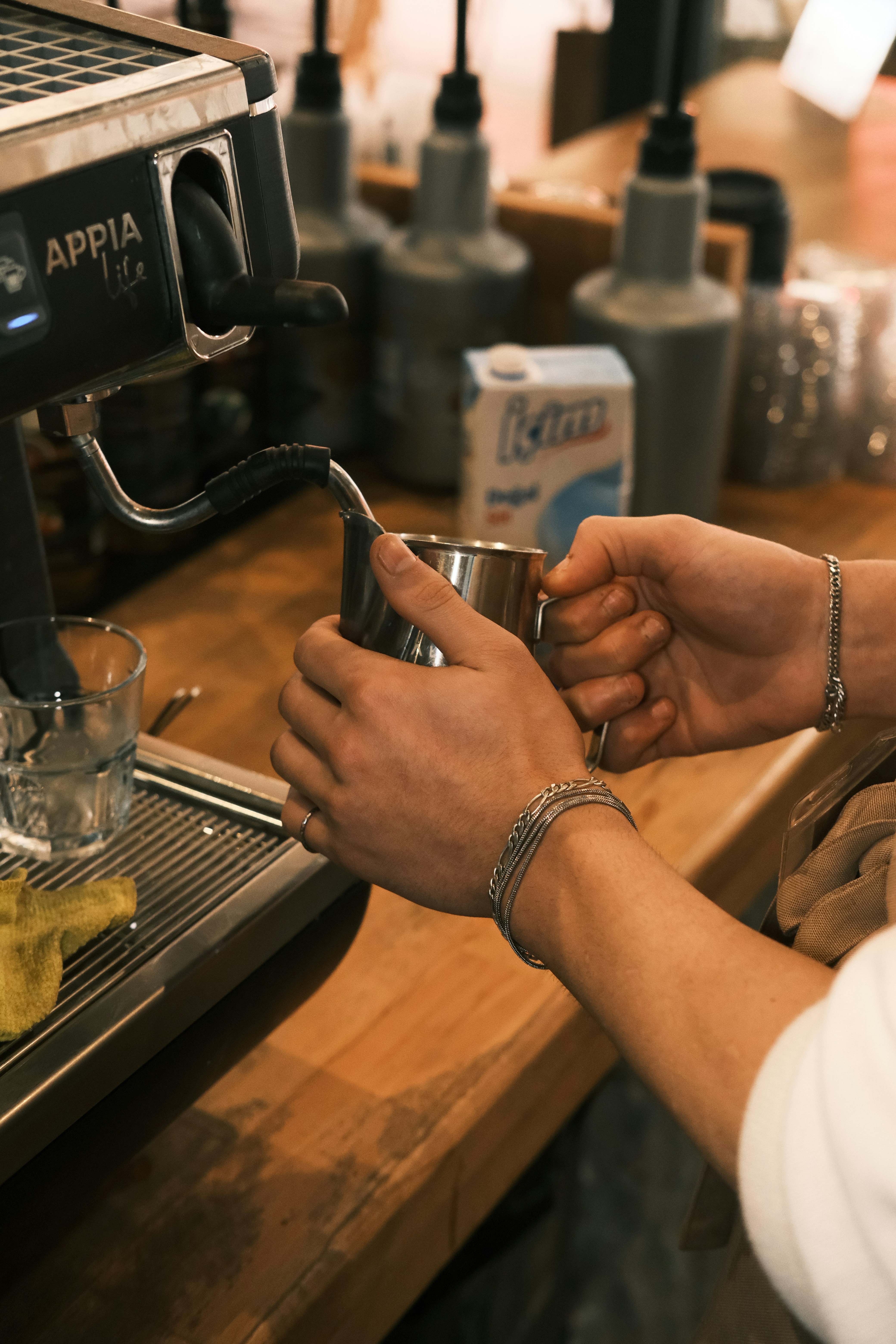 Top-down view of barista tools arranged neatly on a dark wooden table: a stainless steel tamper, a bottomless portafilter, fresh coffee beans scattered, a digital scale, and a V60 dripper. Minimalist and clean.
