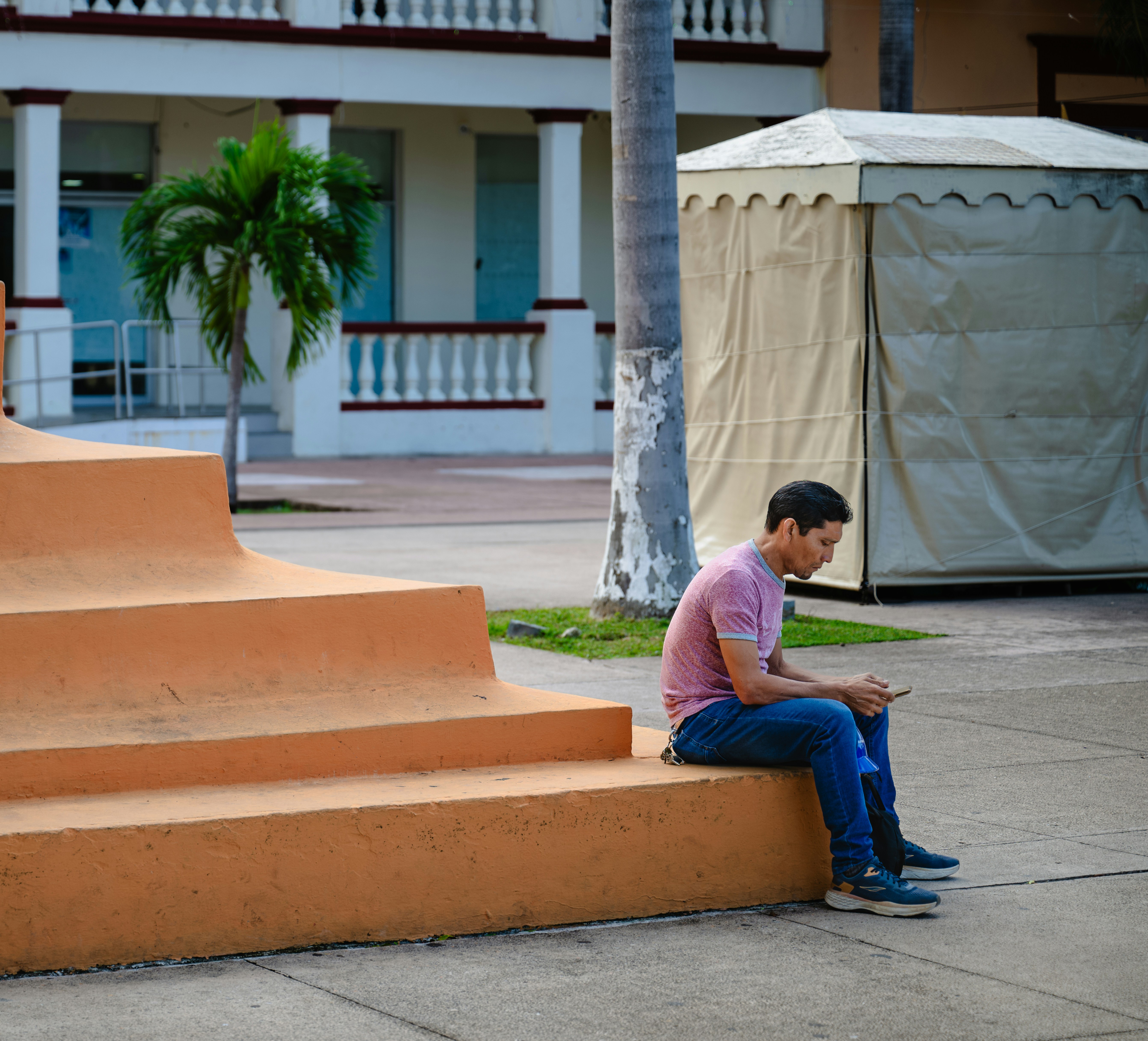 A man sitting on a set of steps looking at his cell phone