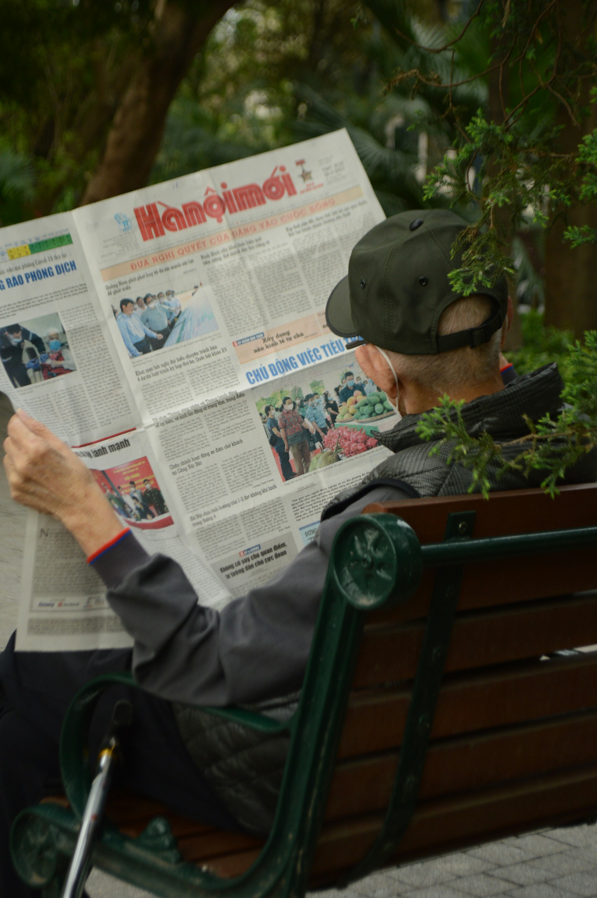 A man sitting on a bench reading a newspaper