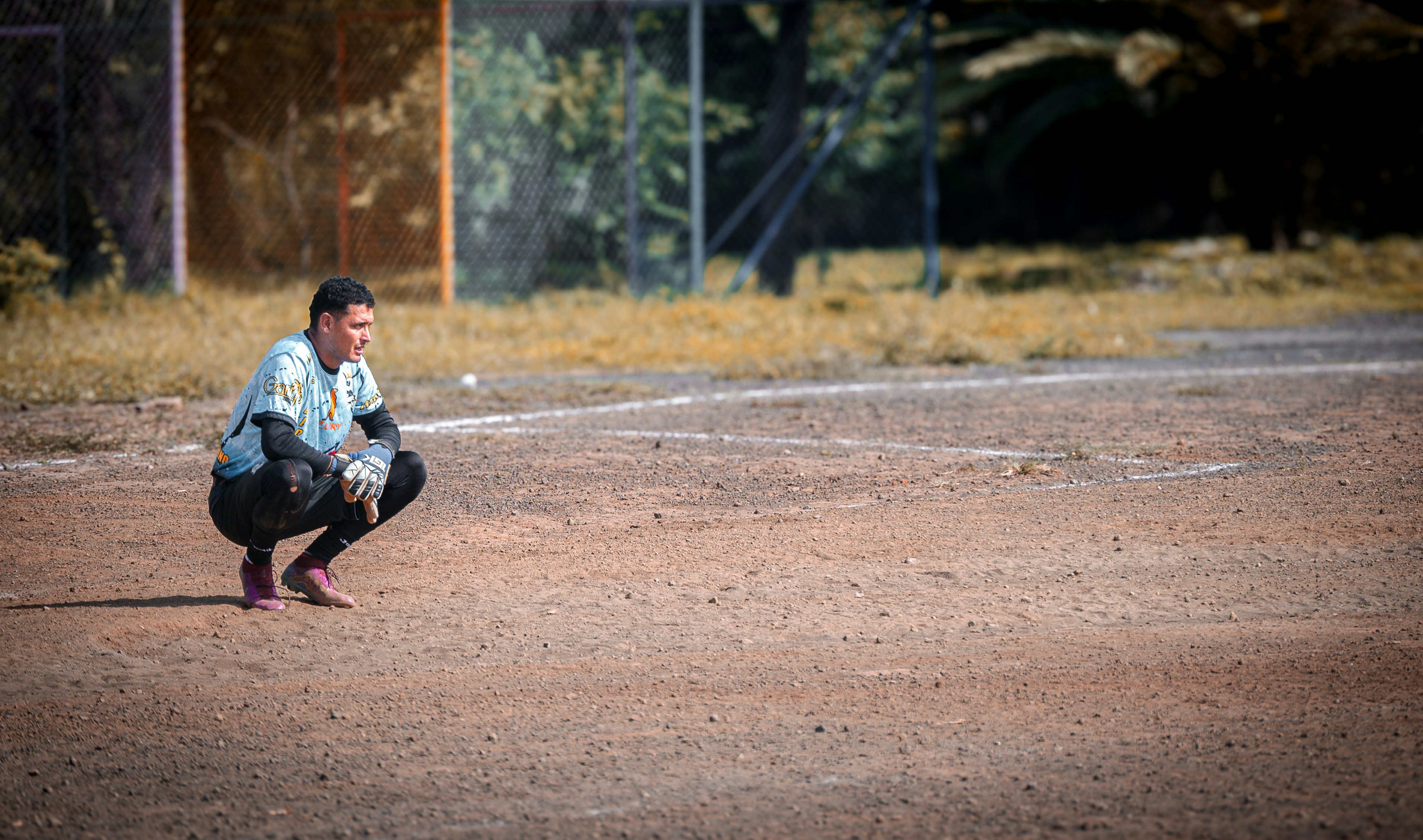 A man kneeling down on a baseball field