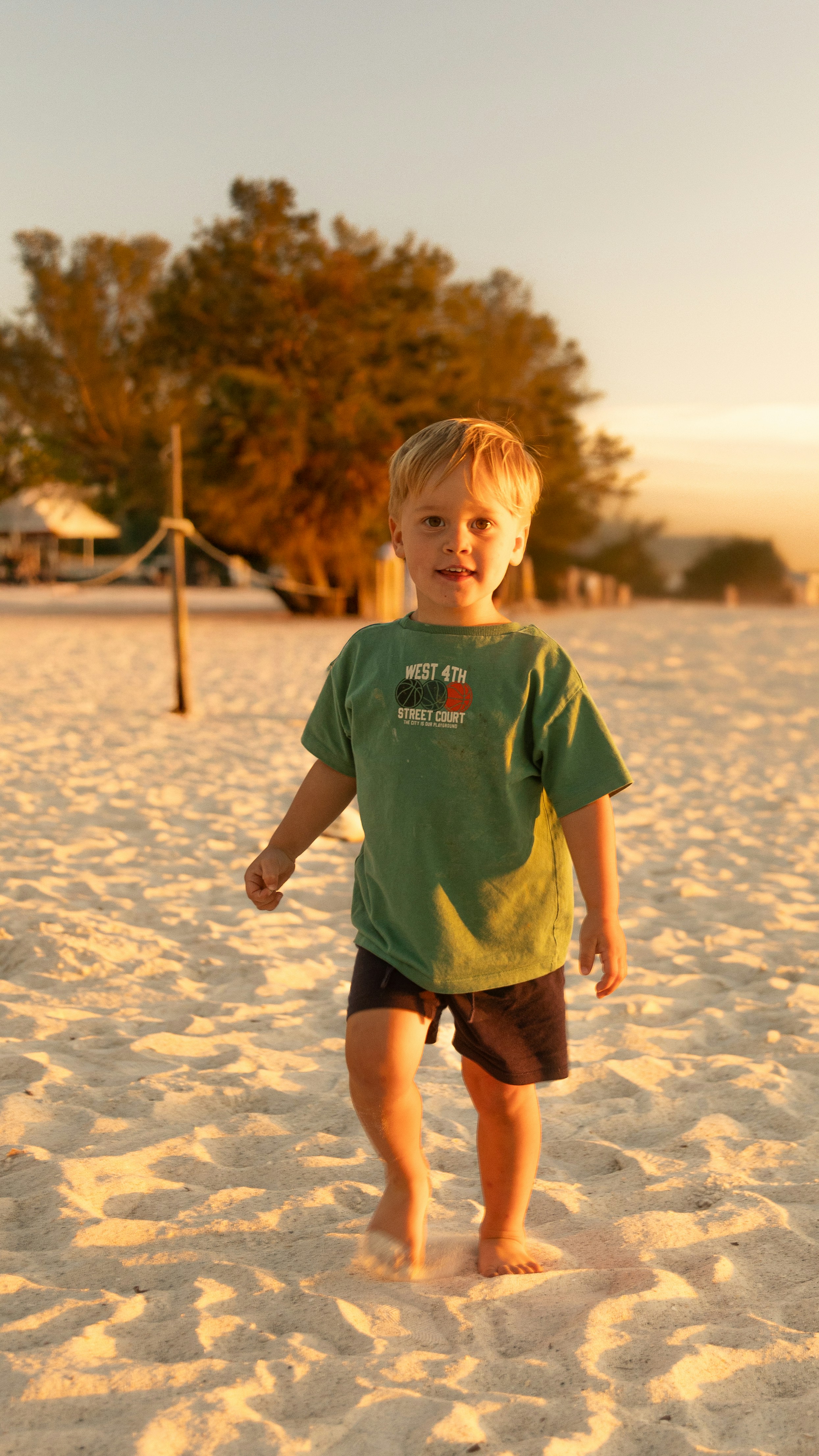 A young boy walking across a sandy beach