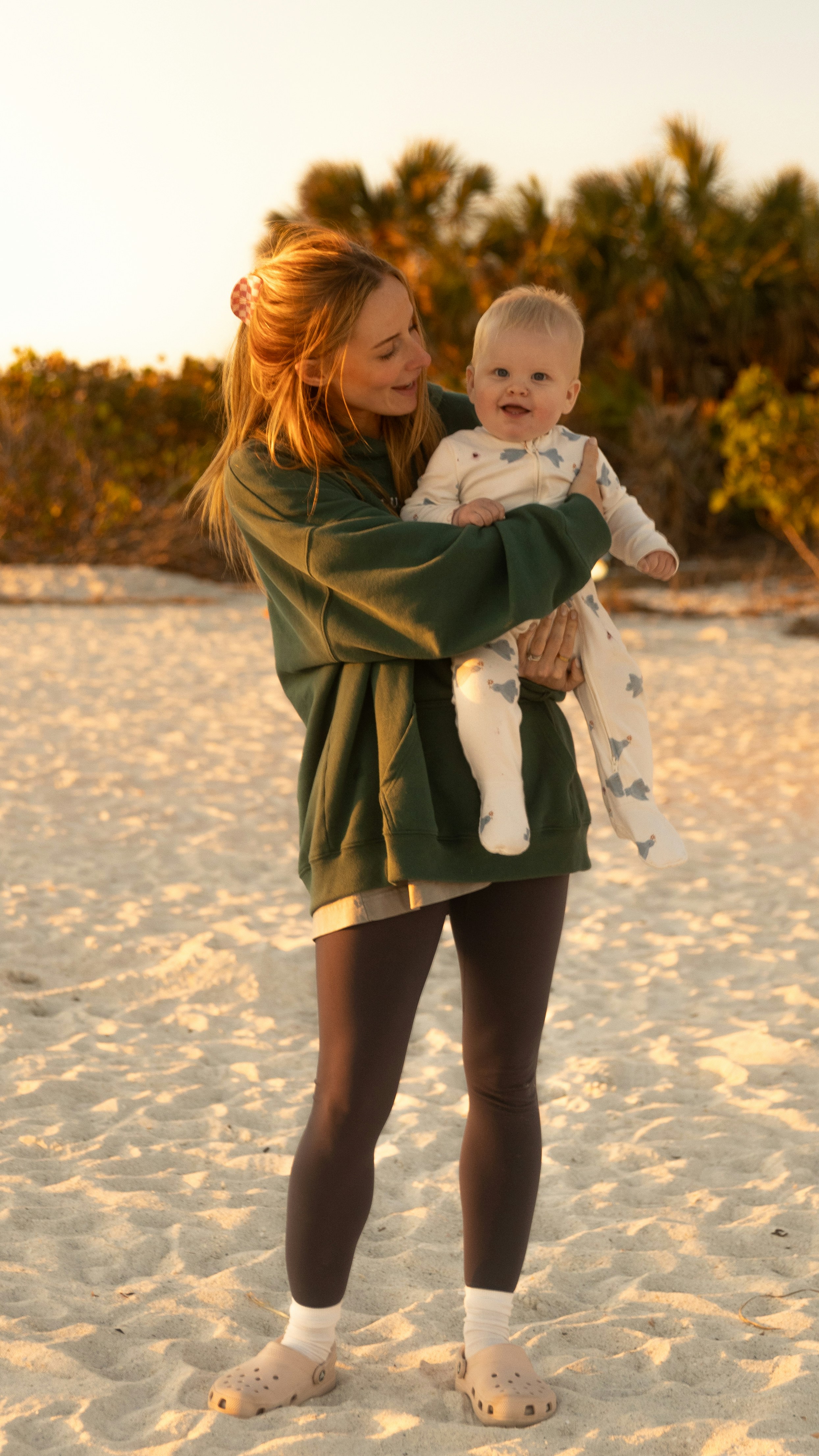 A woman holding a baby on a sandy beach