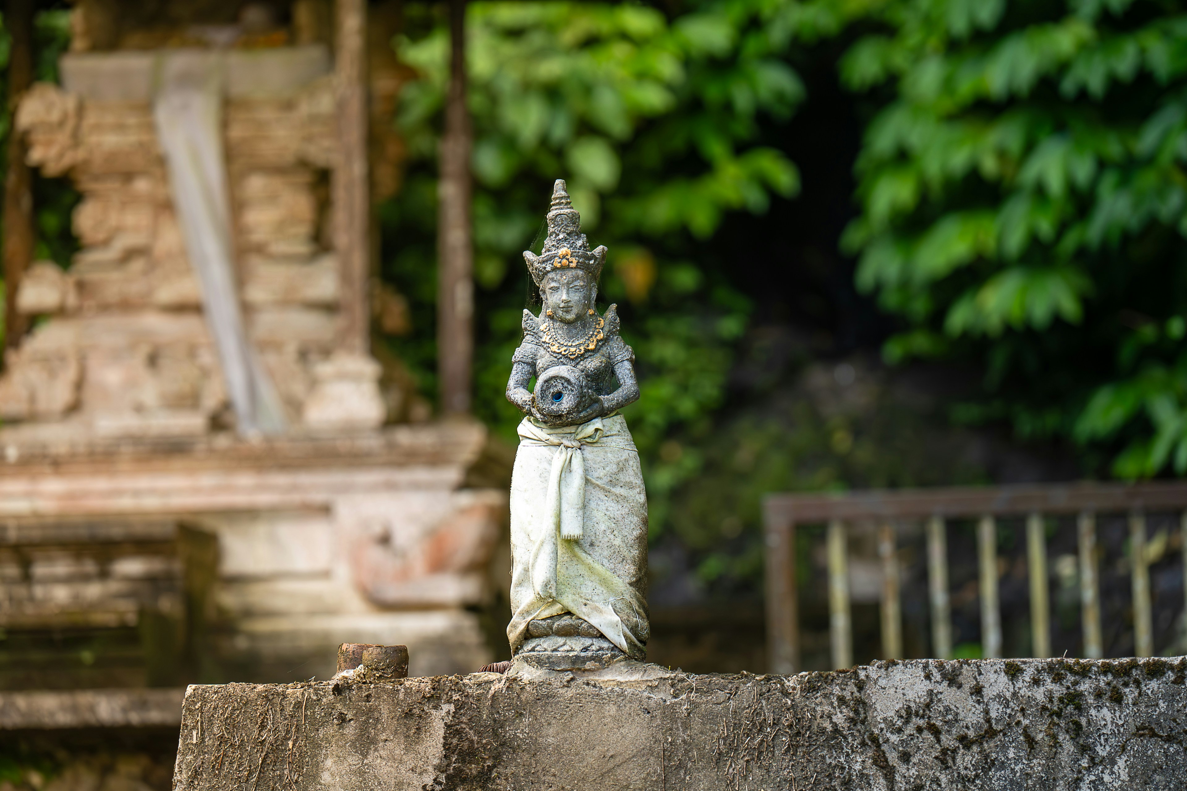 A statue sitting on top of a stone wall