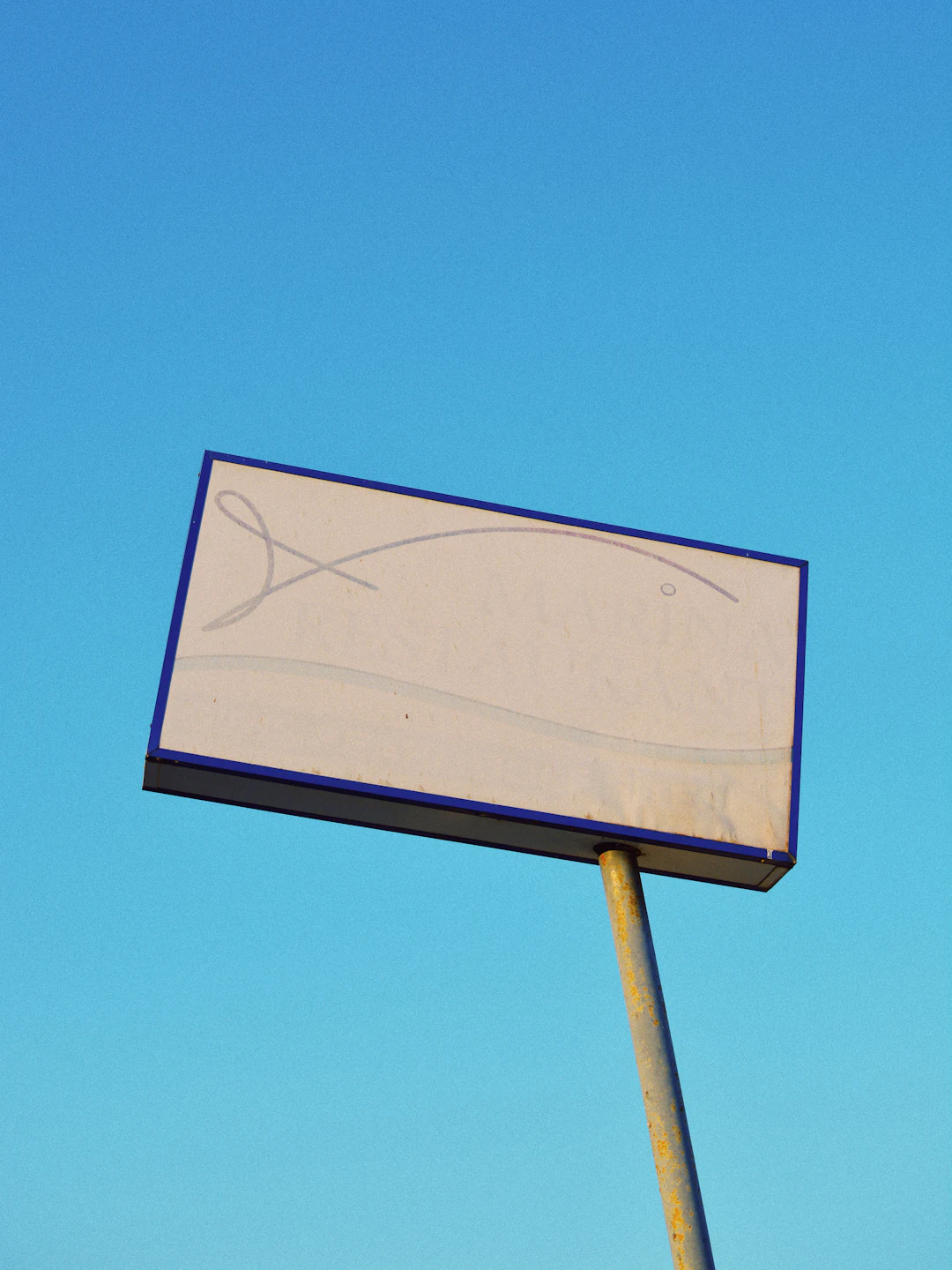 A blank billboard on a pole against a clear blue sky