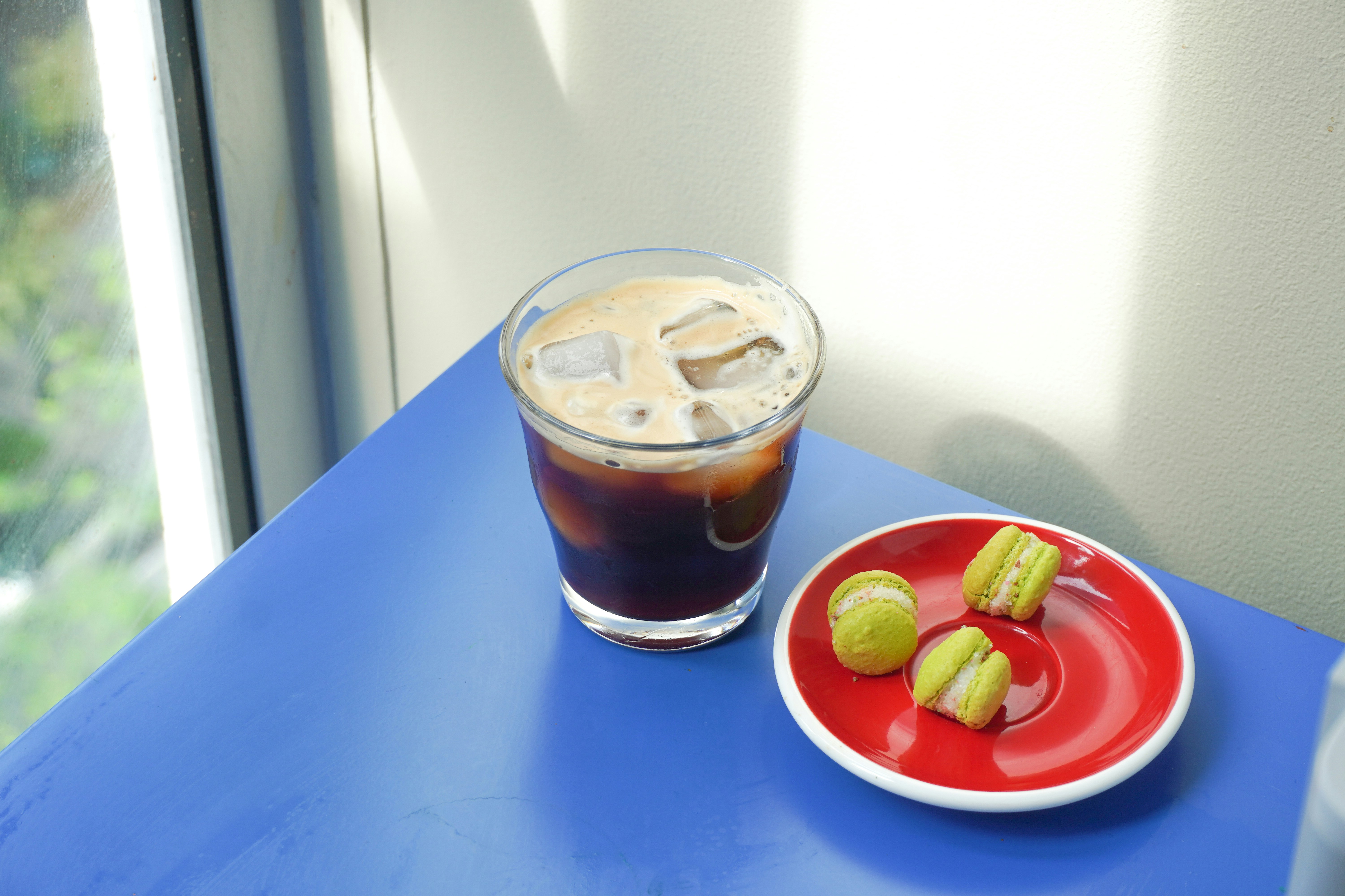 A red plate topped with apples next to a cup of coffee