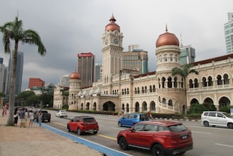 A red car driving down a street next to tall buildings