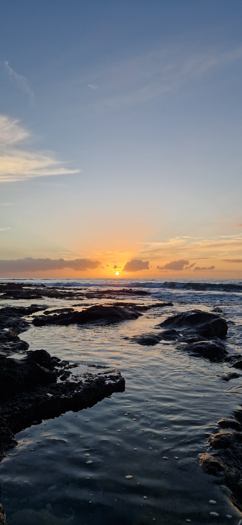Le soleil se couche sur l'océan et les rochers