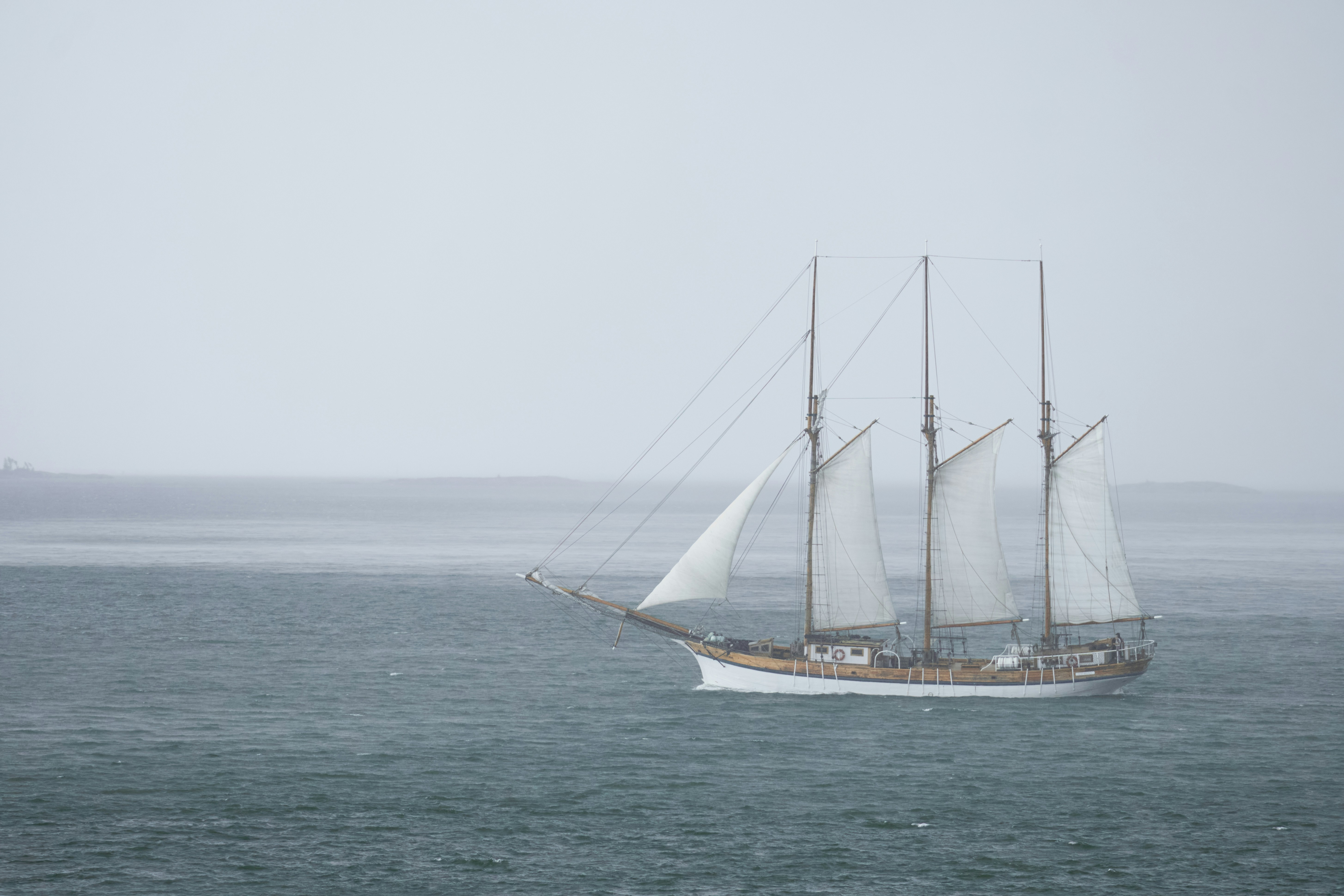 A sailboat sailing in the ocean on a foggy day