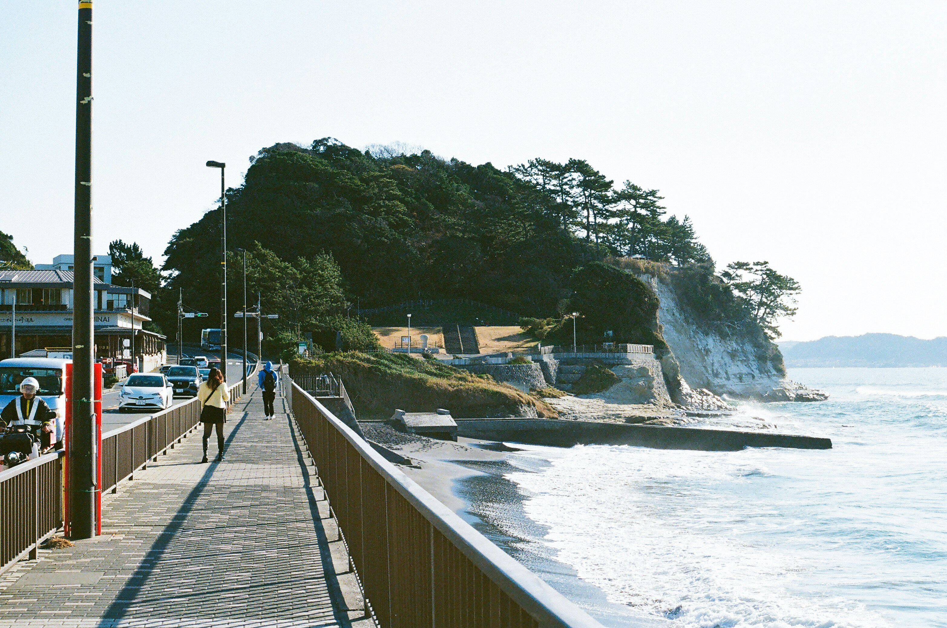 A man walking down a sidewalk next to the ocean