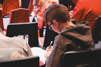 A boy sitting in a chair writing on a piece of paper