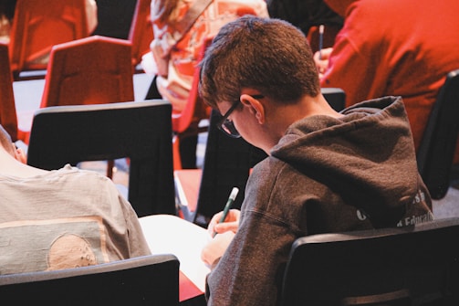A boy sitting in a chair writing on a piece of paper