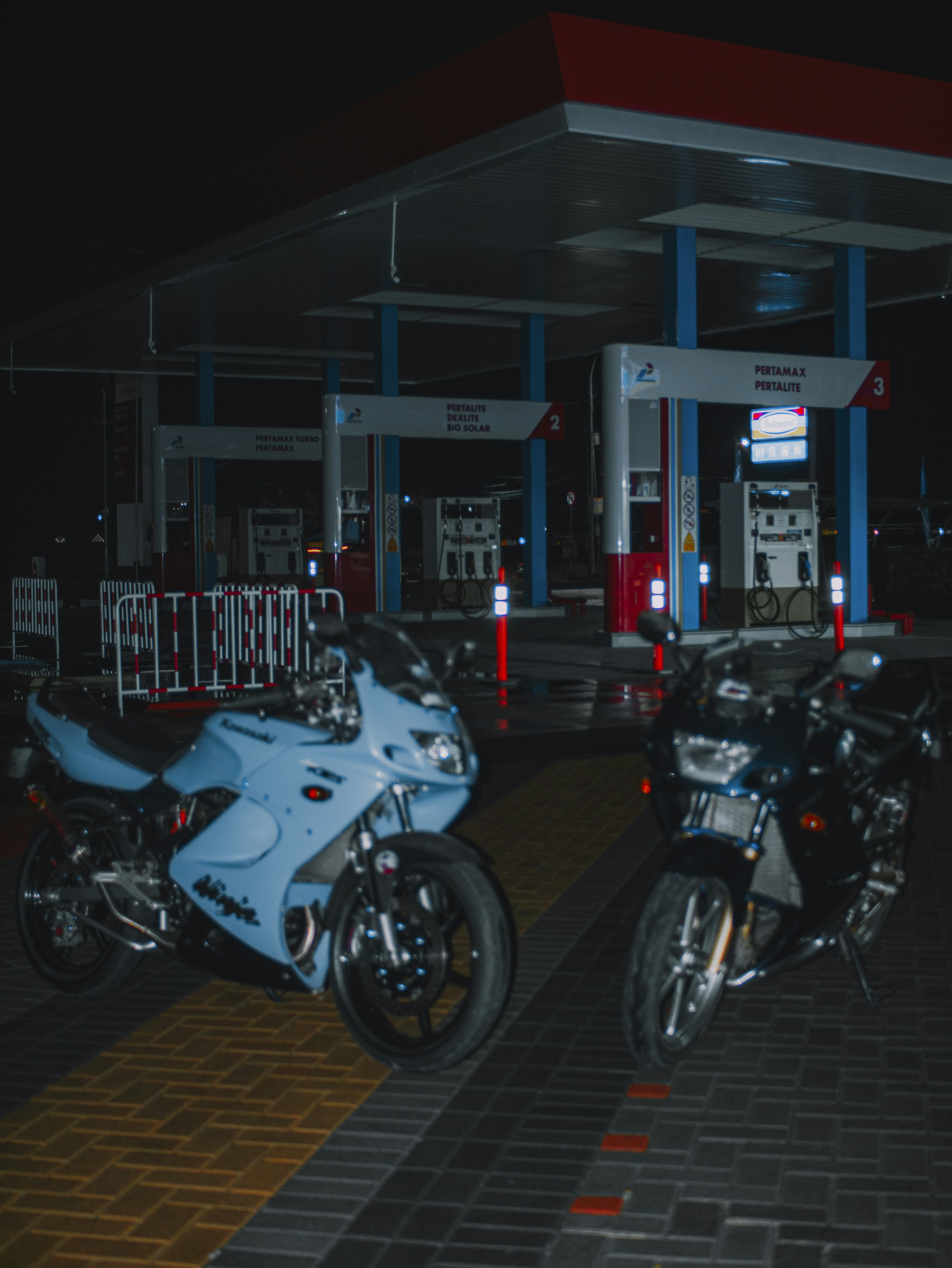 Dua sepeda motor diparkir di depan pompa bensin