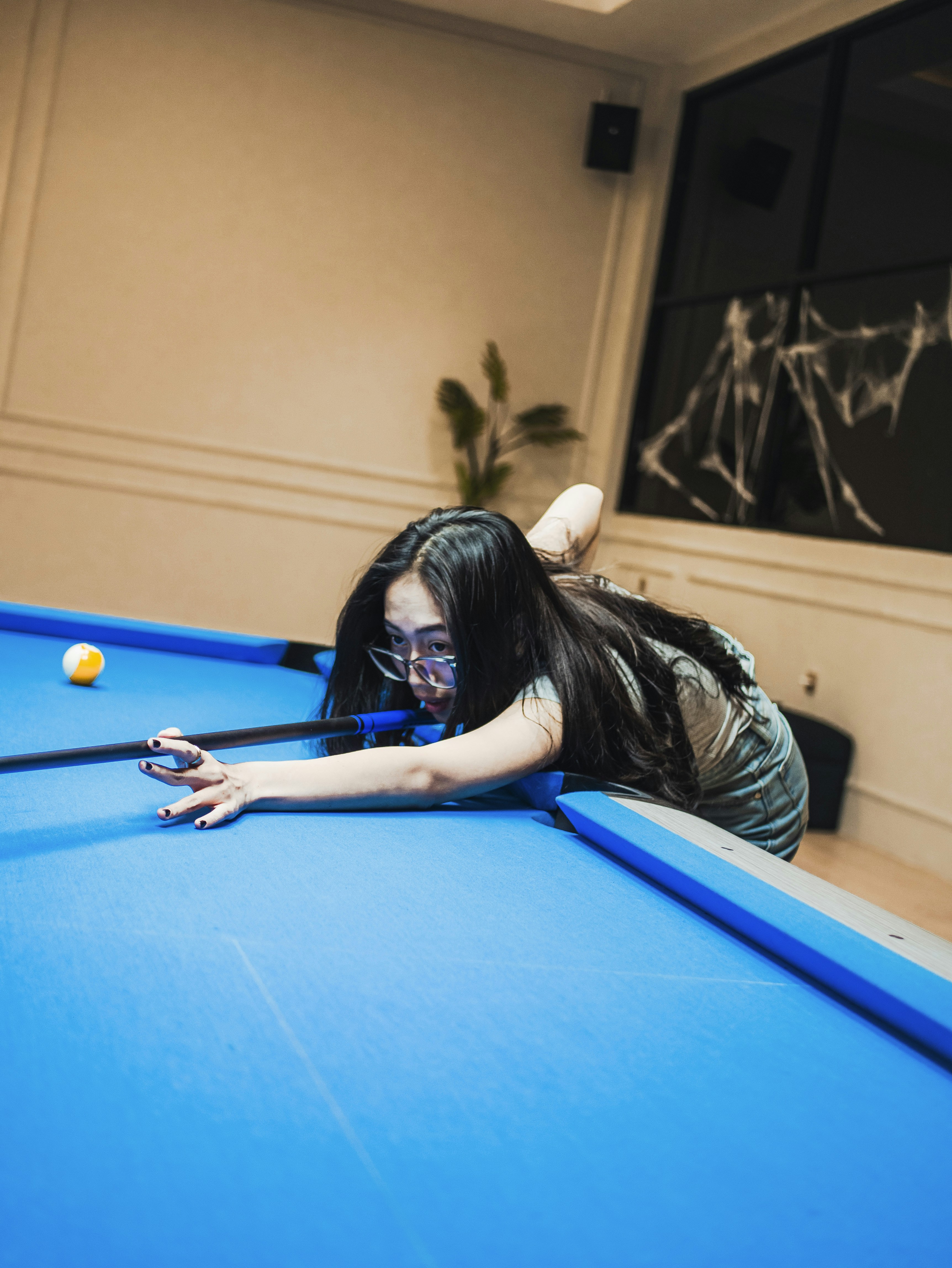 A woman laying on top of a blue pool table