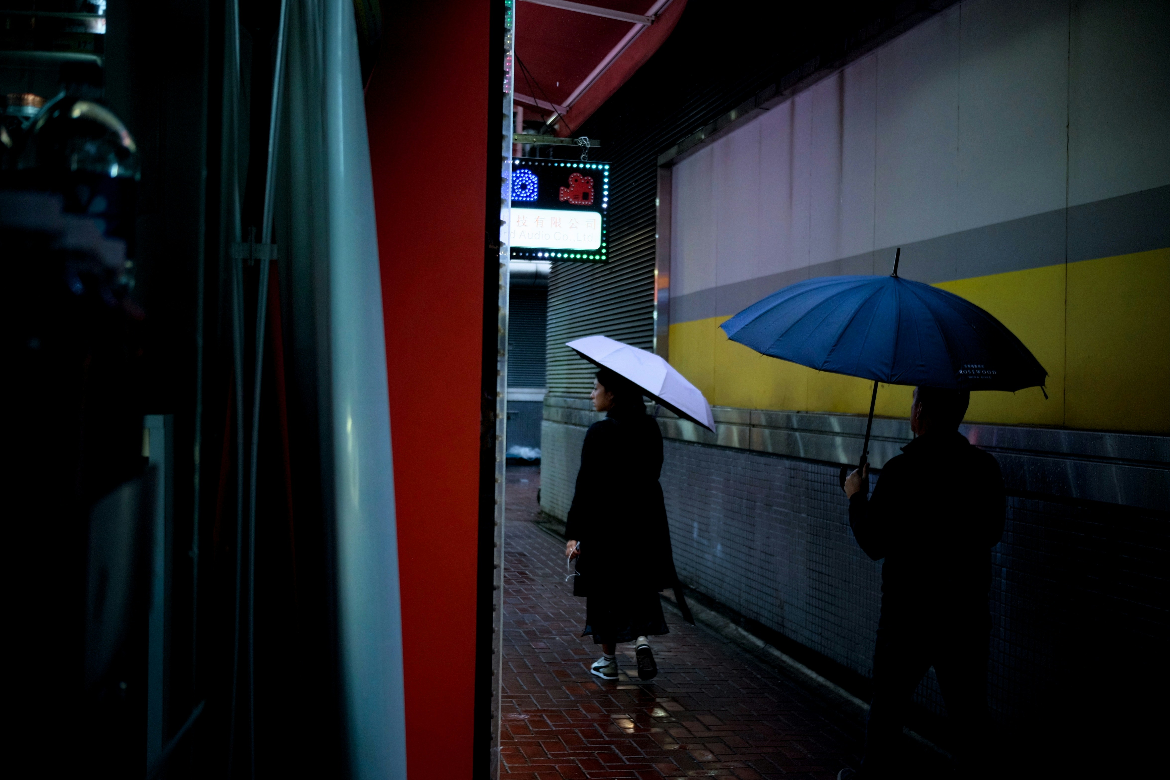 A couple of people walking down a street holding umbrellas