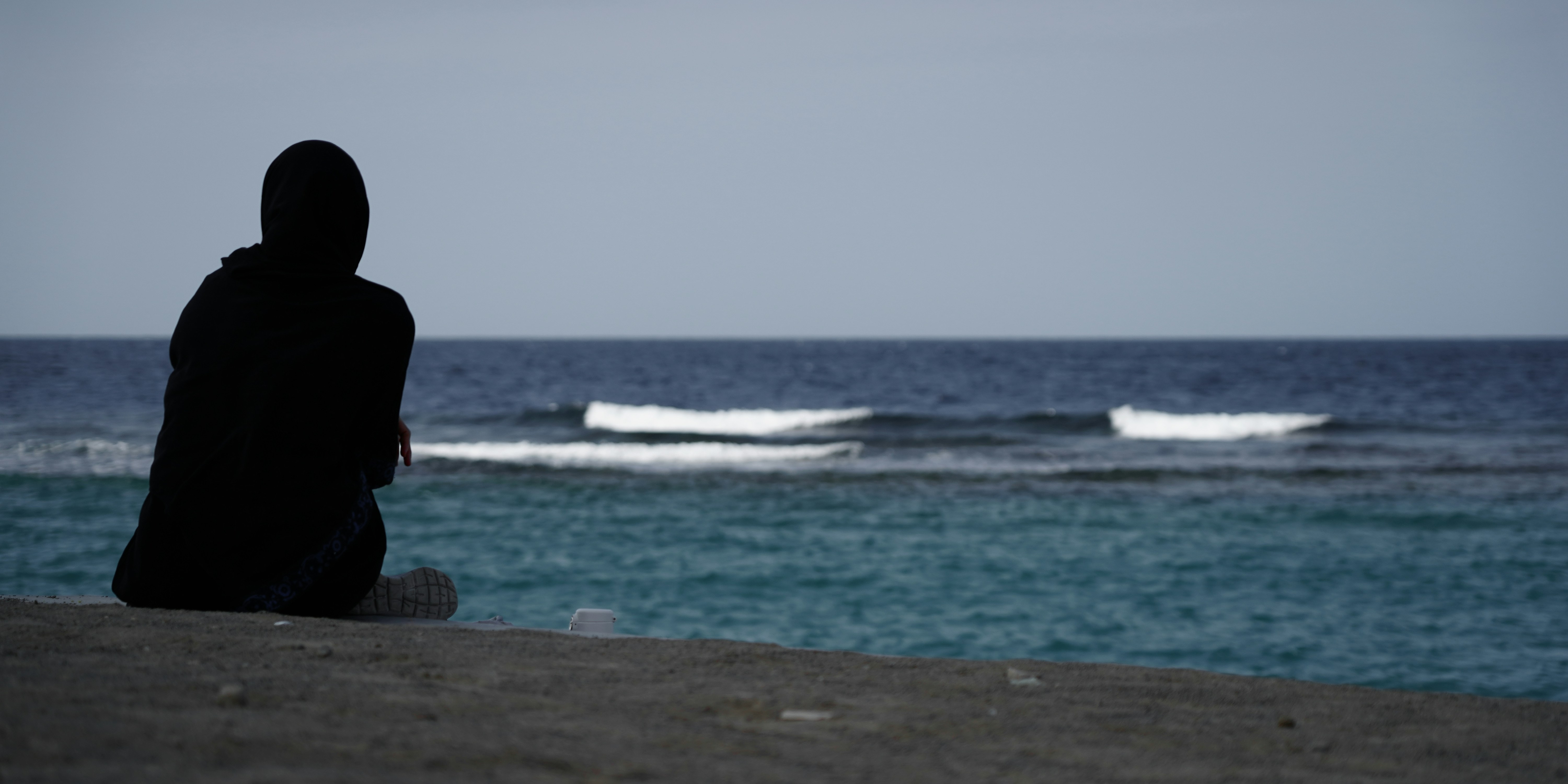A person sitting on a beach looking out at the ocean photo – Free Sea ...