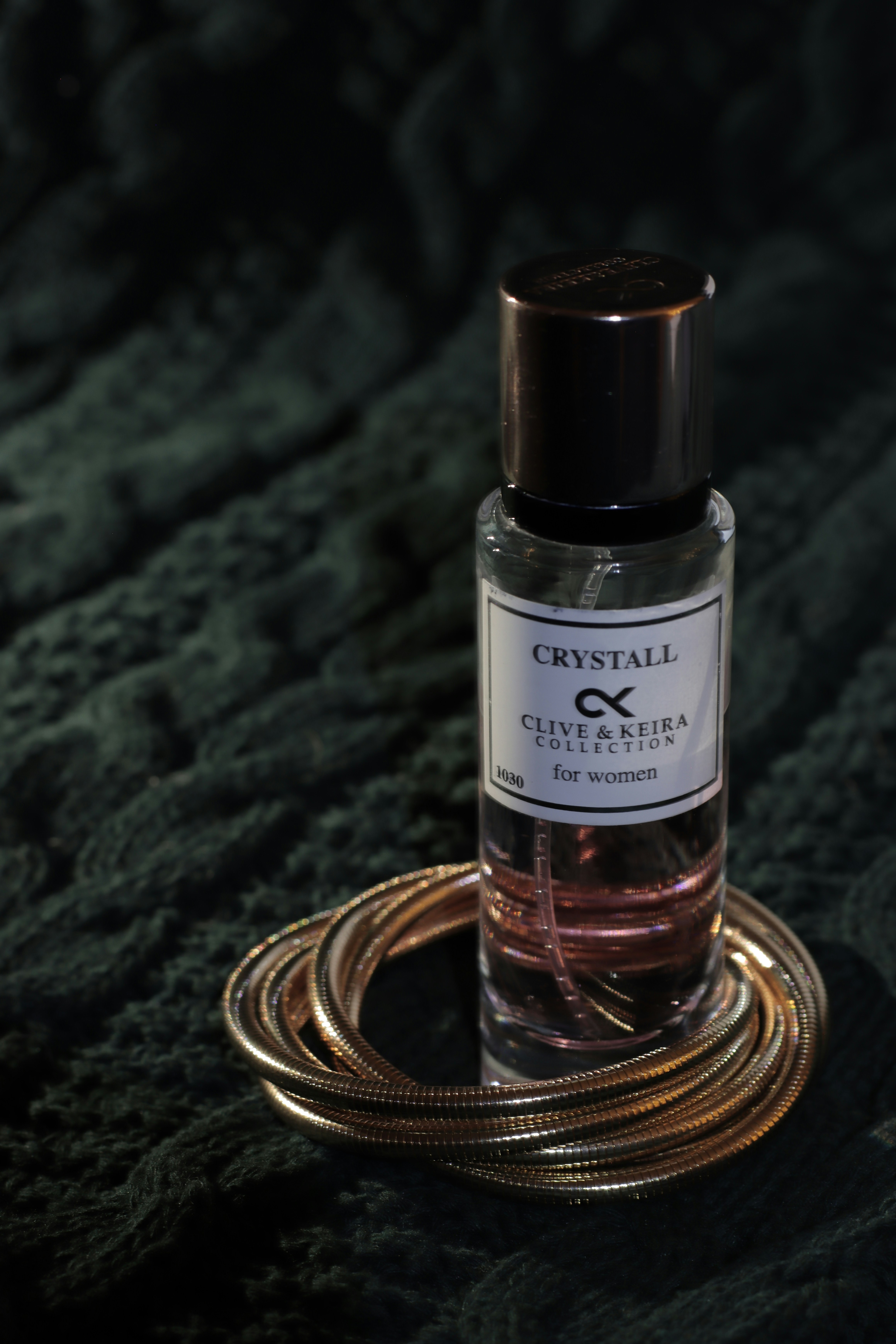 Una bottiglia di profumo seduta sopra una coperta verde